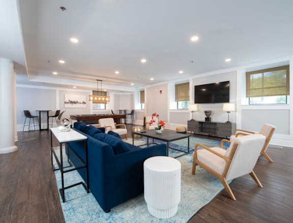 A living room with a blue couch and a white ottoman.