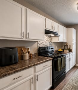 A kitchen with white cabinets and a black fridge. at Woodwinds, South Carolina, 29803