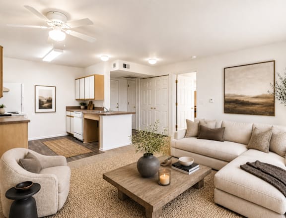 A living room with a white couch, a grey armchair, a wooden coffee table, and a painting on the wall.