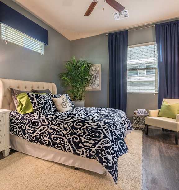 A living room with a couch, a chair, a table, a rug, and a ceiling fan.