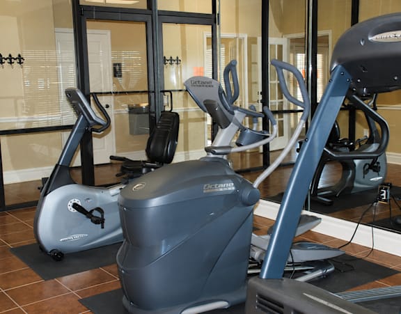 A gym with a treadmill, elliptical trainer and a stationary bike.