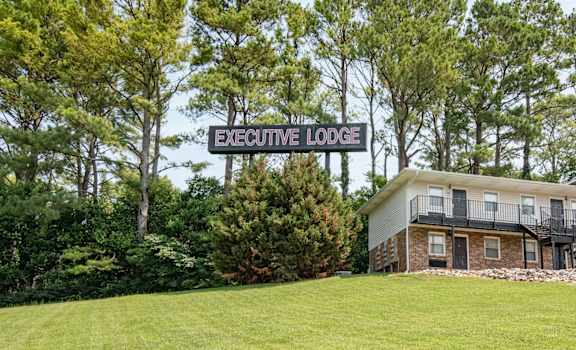 a building on a grassy hill with a sign that reads executive lodge