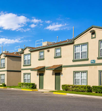 Apartment complex with a parking lot in front.