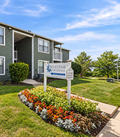A sign for Bluestar Crossing in front of a building.