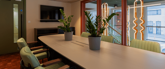 a conference room with a table and chairs and potted plants