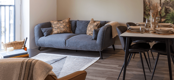 a living room with a blue couch and a table with chairs