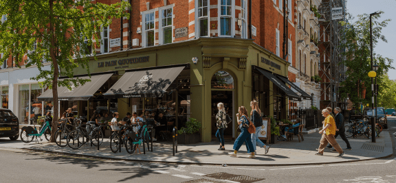 people walking on a city street in front of a restaurant