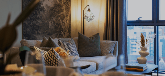 a living room with a couch and pillows and a window
