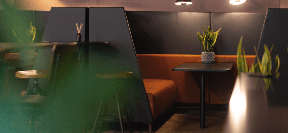 a restaurant with orange booths and a table with a potted plant