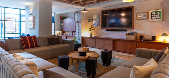 A living room with a large couch and a flat screen TV mounted on the wall.