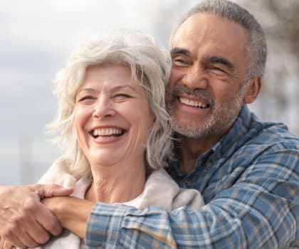 an older man and woman laughing with their arms around each other