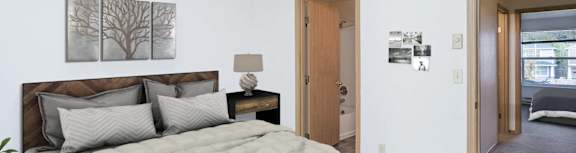 A bedroom with a bed, nightstand, and a painting on the wall.