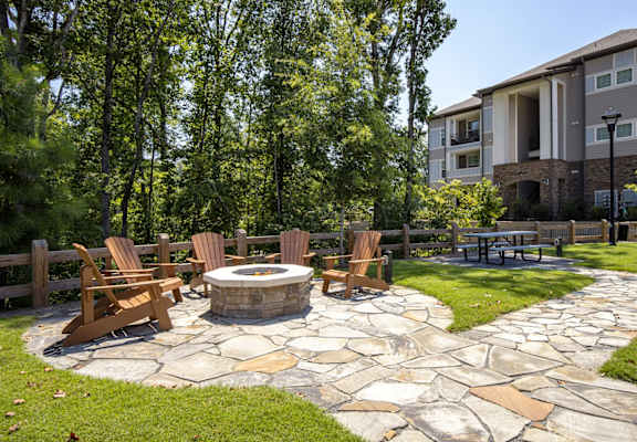 a stone patio with a fire pit and chairs