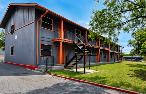 A modern building with a red and grey exterior and a black metal staircase.