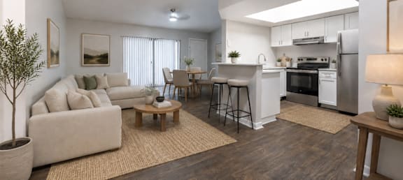 A modern living room with a white couch, a wooden coffee table, and a kitchen area in the background.
