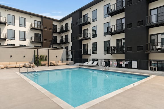 A large swimming pool in front of apartment buildings.
