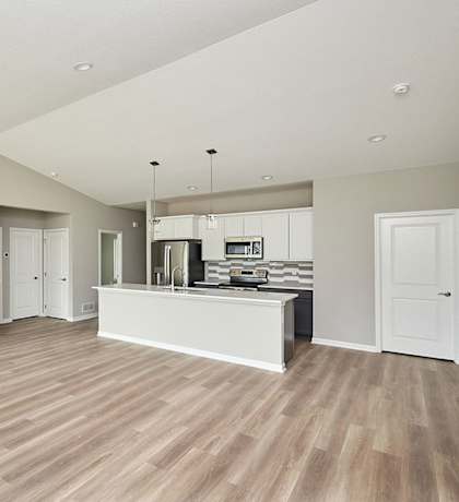 A spacious kitchen with a bar counter and a refrigerator. at Two Rivers Home Rentals, West Des Moines, IA