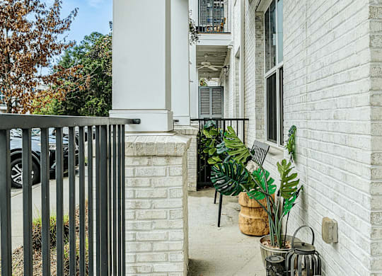 A white house with a black gate and plants on the porch.