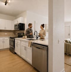 A man and woman are standing in a modern kitchen.