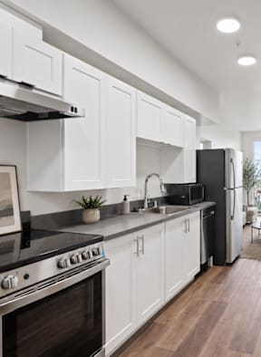 A modern kitchen with white cabinets and a black stove top oven.