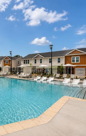 A large swimming pool surrounded by lounge chairs and umbrellas.