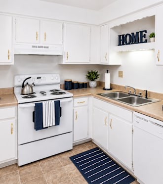A white kitchen with a sign that says "HOME" on the wall.