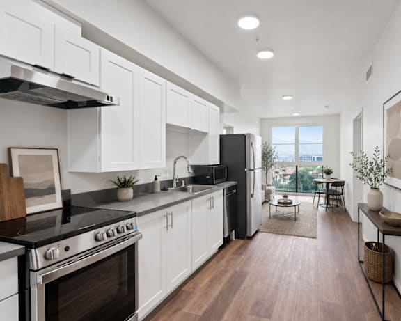 A modern kitchen with white cabinets and a black stove top oven.