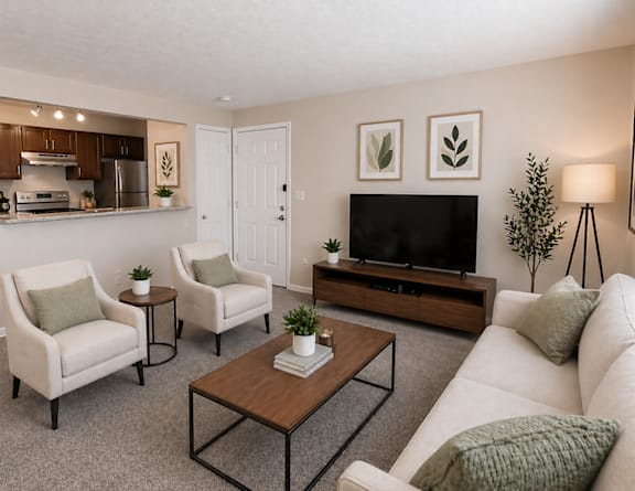 A living room with a white couch, two chairs, a coffee table, and a television.