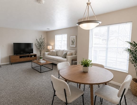 A living room with a grey carpet and a wooden coffee table.
