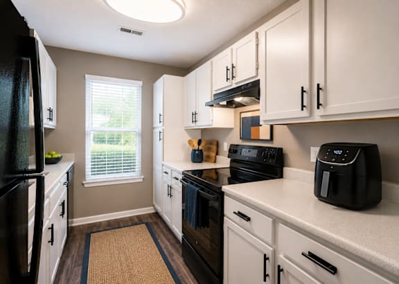 A black stove in a kitchen with white cabinets. at Woodwinds, Aiken, 29803