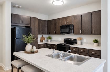 Professionally staged kitchen with breakfast bar at Townes at Clarkston Centre apartments in Clarkston, GA.
