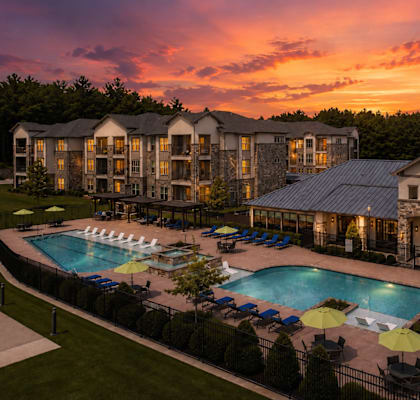 Resort-style pool at sunset with beautifully lit apartment homes at Auberge of Tyler.