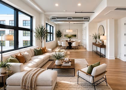 A well-lit, modern living room with a large white sofa and a coffee table.