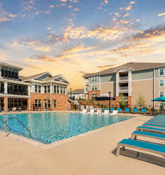 A large swimming pool in front of a building with a sunset in the background.