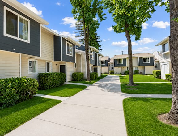 A row of houses with a sidewalk in front.