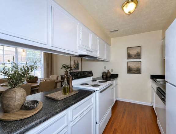 A kitchen with white cabinets and a black countertop.