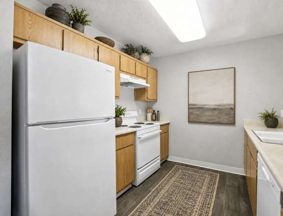 A kitchen with a white refrigerator and wooden cabinets.