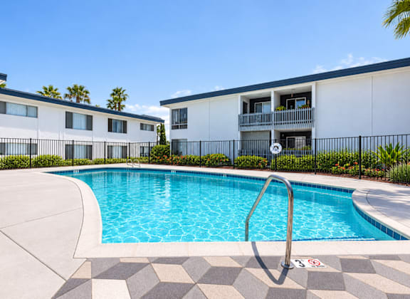 A swimming pool in front of a building with a metal fence.