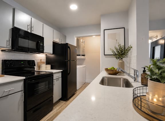 A modern kitchen with black appliances and white cabinets.