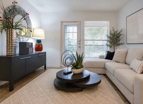 A living room with a white couch, a coffee table, and a plant.