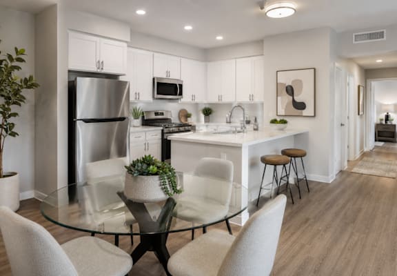 A modern kitchen with a glass table and white chairs.