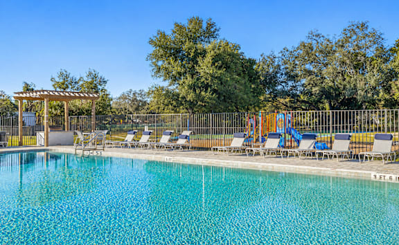 a resort style swimming pool with lounge chairs and umbrellas