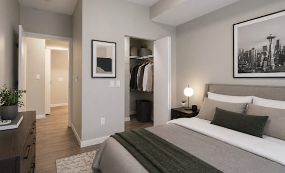 A bedroom with a bed, nightstand, and a plant.