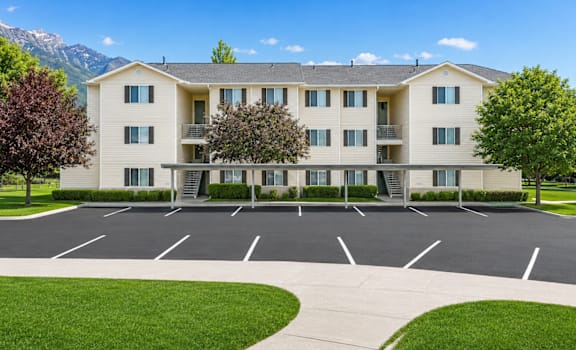 A large apartment complex with a parking lot in front.