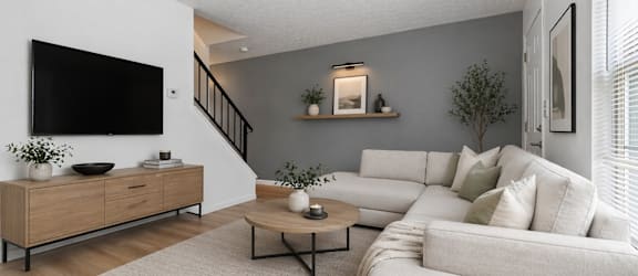 A living room with a white couch, a wooden cabinet, and a staircase.