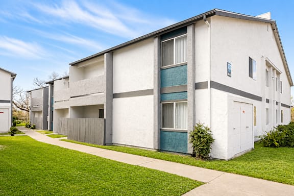 A white apartment building with a green door and a grey fence.