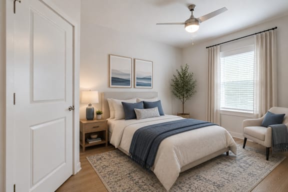 Bright guest bedroom at Blue Sky Landing featuring a spacious layout, ceiling fan, plush carpeting, and natural light in a thoughtfully designed apartment home in College Park, GA.