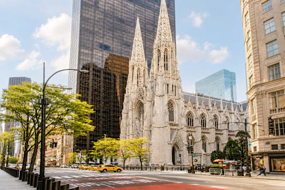 A large cathedral with a tall spire stands in front of a modern glass building.