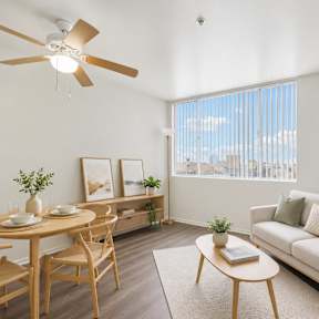 A living room with a couch, table, chairs, and a ceiling fan.