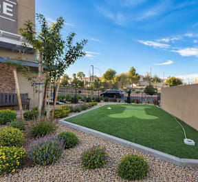A small putting green is surrounded by a low fence and a sign that says "Pet Waste.".